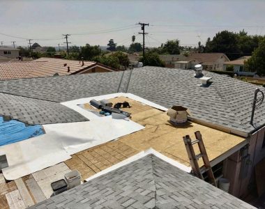 A worker installs a roof using tar and plastic sheeting, showcasing the roofing process in progress.